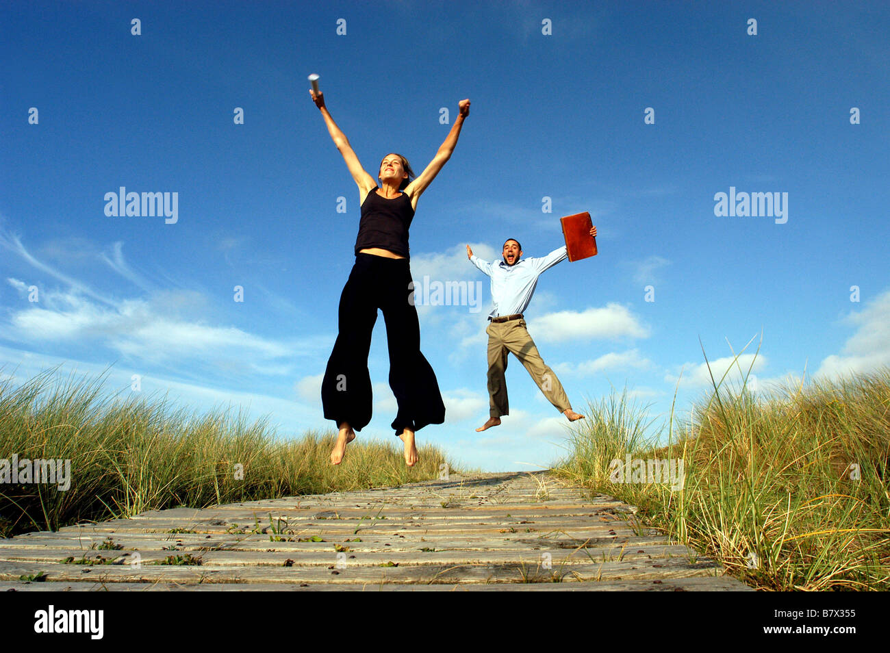 Businessman and businesswoman sauter dans l'air pour célébrer la réussite sur la côte sud-ouest Banque D'Images