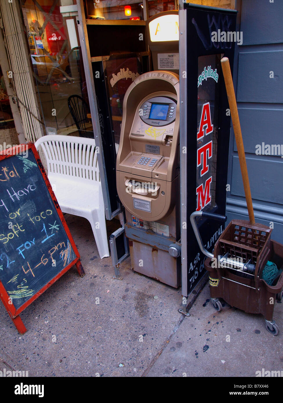 Un guichet automatique, d'une vadrouille, d'un seau, et tableau noir en face d'un café sur un trottoir de la ville de New York dans le Greenwich Village. Banque D'Images