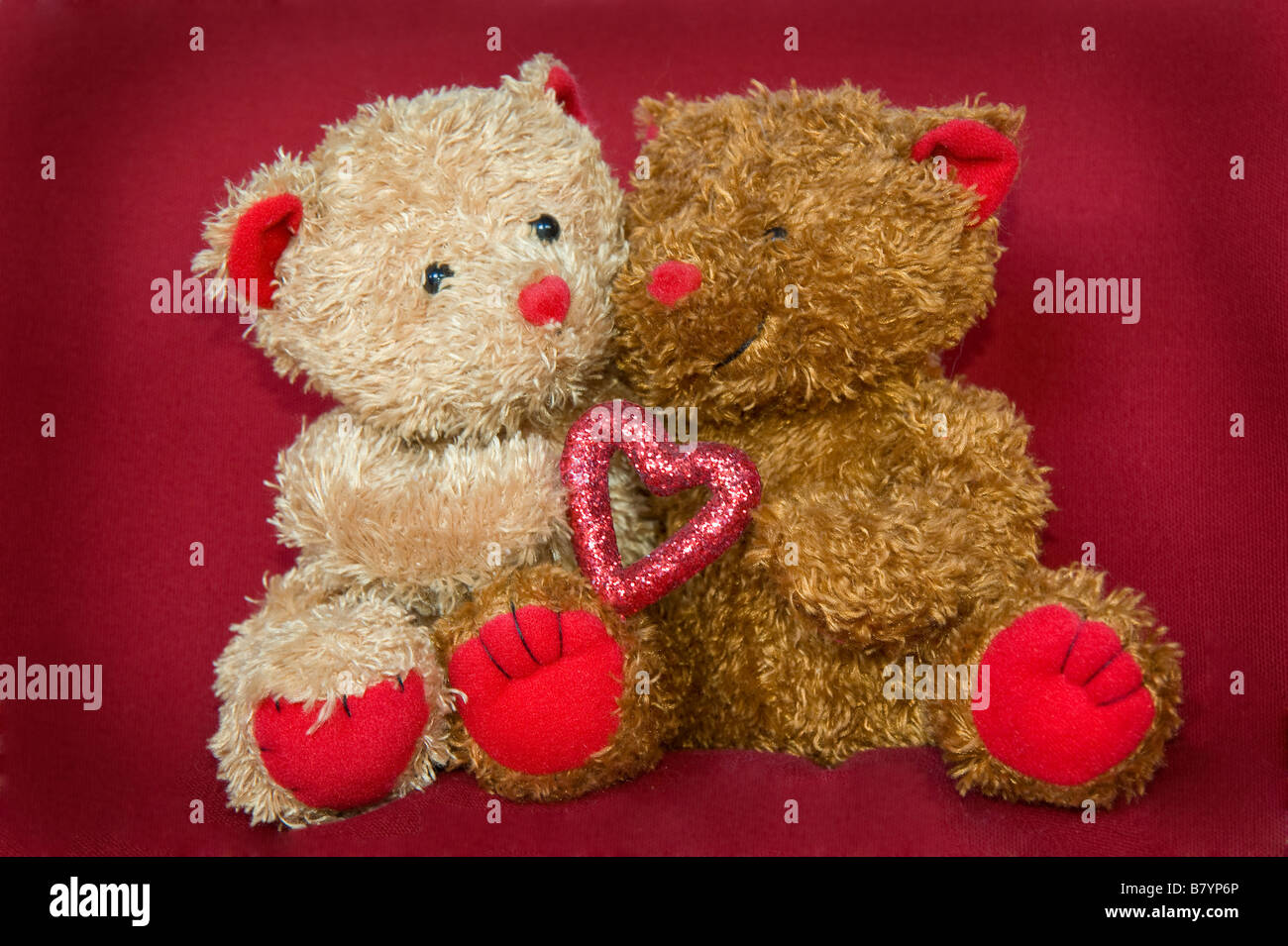 Deux mignon nounours tenant un cœur sur fond rouge Photo Stock - Alamy