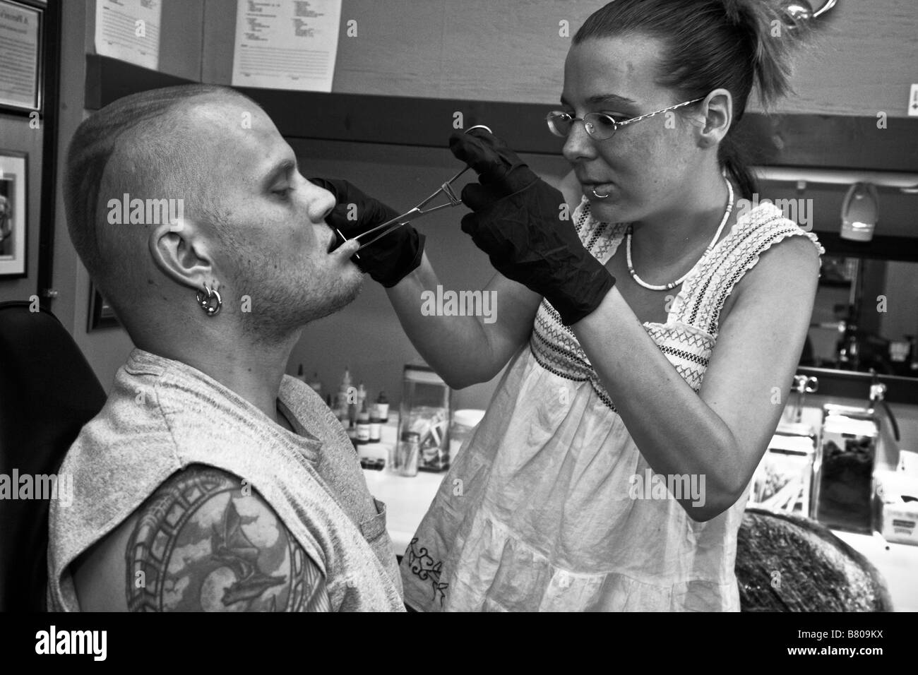 Tracy Baker, un apprenti perceur à un salon de tatouage à Rockland, Maine, perce la lèvre de Sean Jeweii, son professeur. Banque D'Images