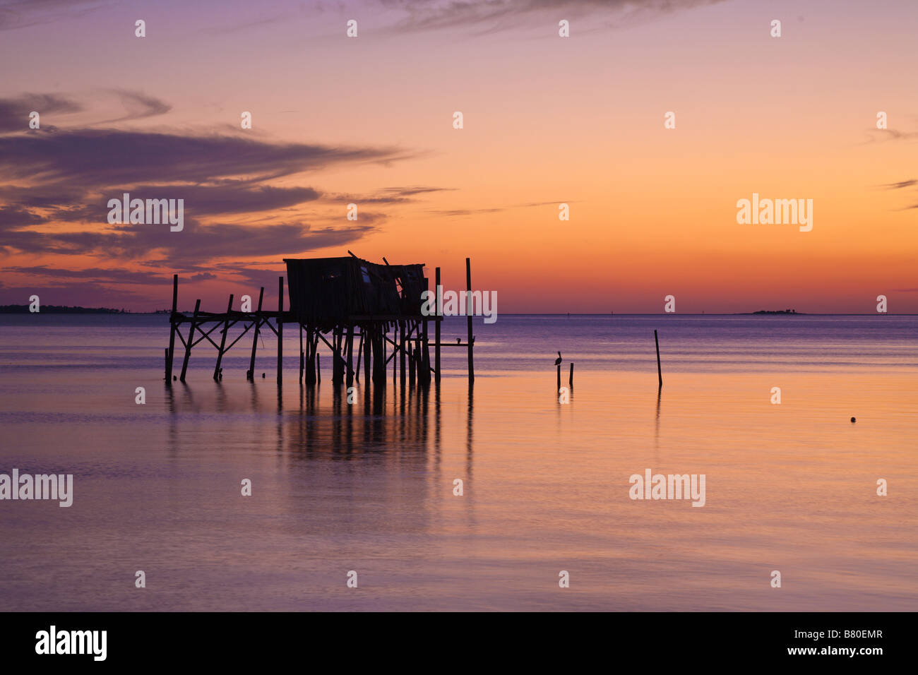 Structure délabrée sur pilotis en silhouette contre orange à Cedar Key, Floride, USA Banque D'Images