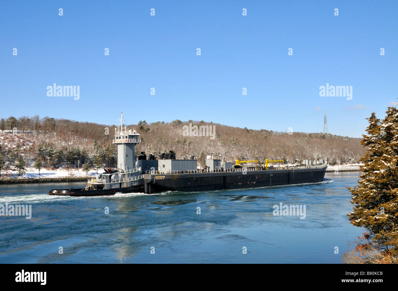 Tugboat pushing gris coque noire barge par Cape Cod Canal en hiver Banque D'Images