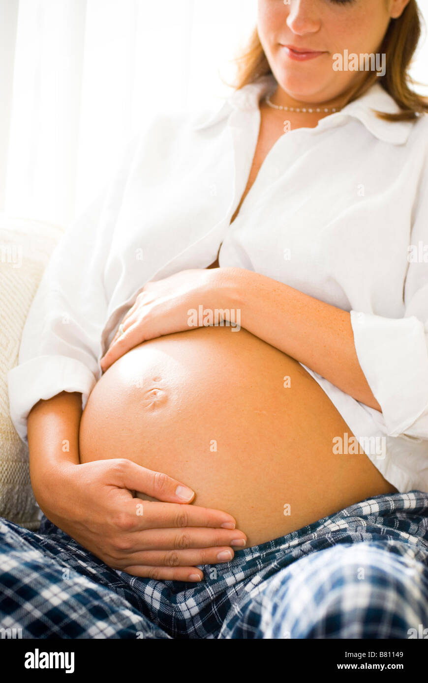 Pregnant woman sitting on couch Banque D'Images