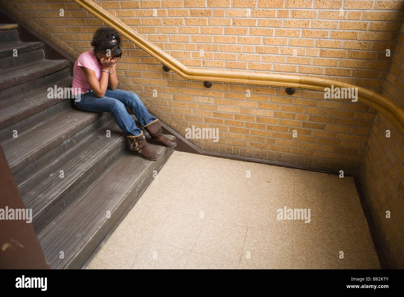 Teenage african american girl de pleurer sur l'escalier à l'école, assis sur l'étape Banque D'Images