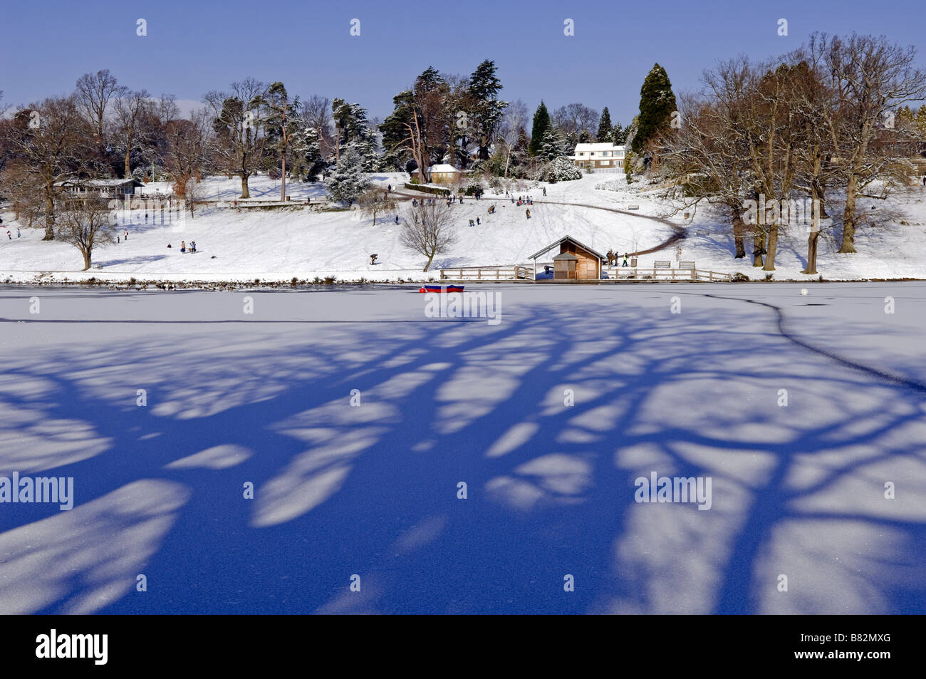 La lumière du soleil à travers des arbres crée des ombres sur le lac gelé à Dunorlan Park à Tunbridge Wells après de fortes chutes de neige en février 2009 au Royaume-Uni Banque D'Images