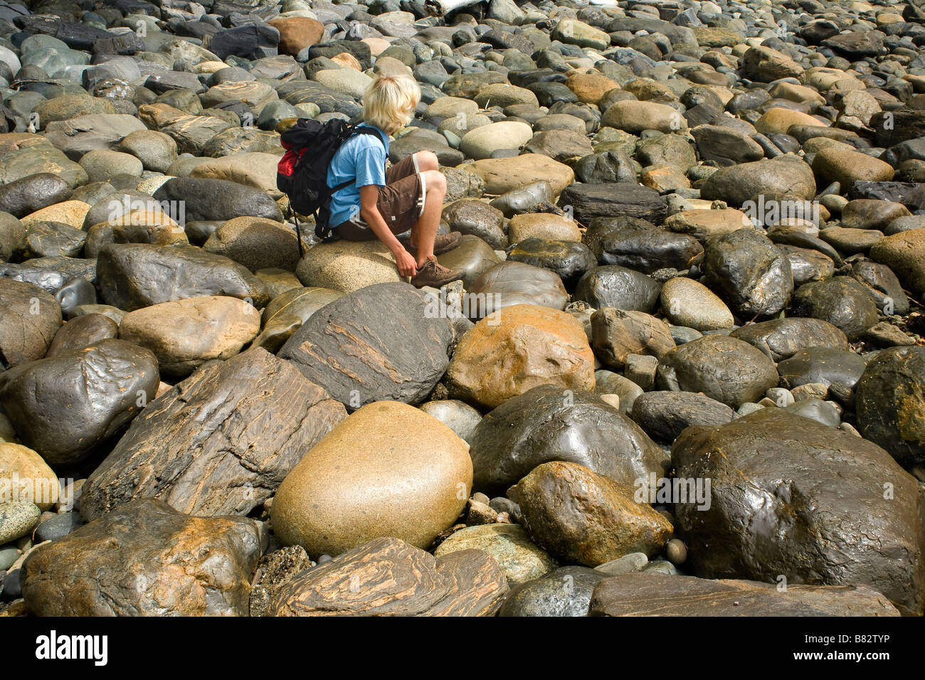 La Colombie-britannique Hiker resting sur rochers sur les arrondis Juan de Fuca Marine Trail à Sombrio Beach. Banque D'Images