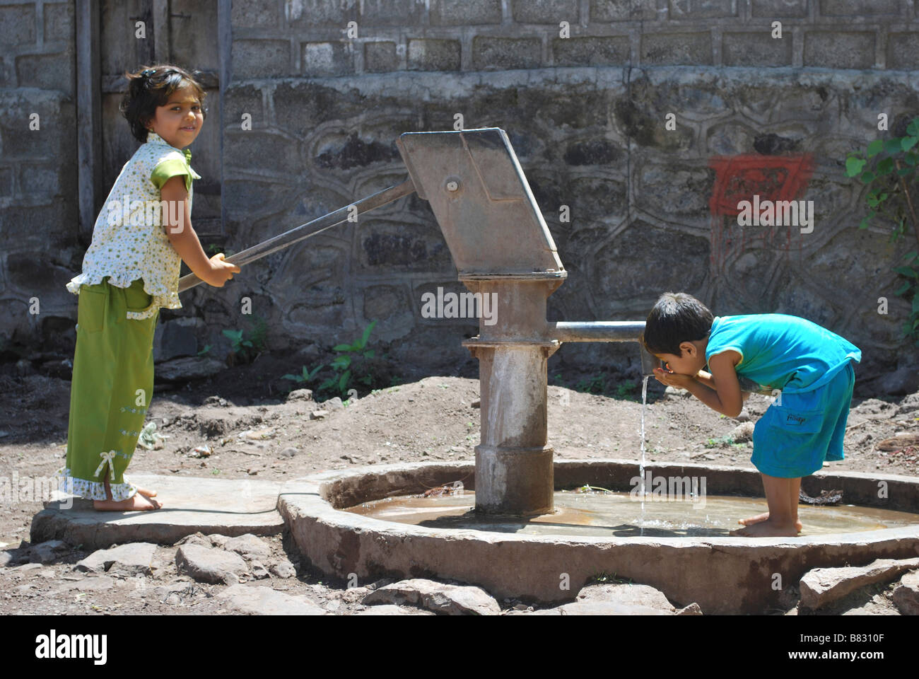 Les enfants à l'aide d'un pompe à eau pour l'eau potable. Satara, Maharashtra, Inde. Banque D'Images