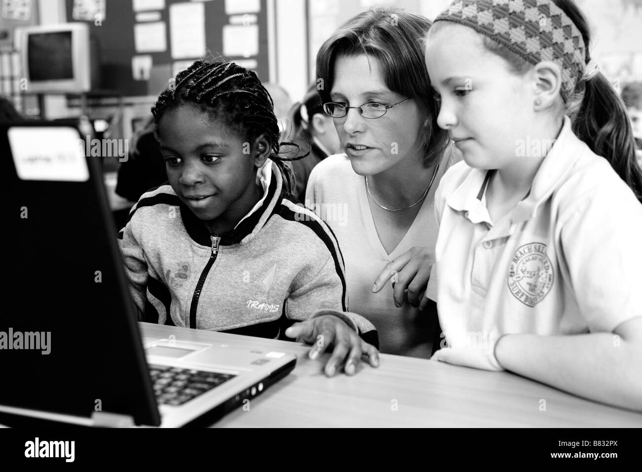 Enseignant travaillant avec les élèves de l'école primaire on laptop computer Banque D'Images