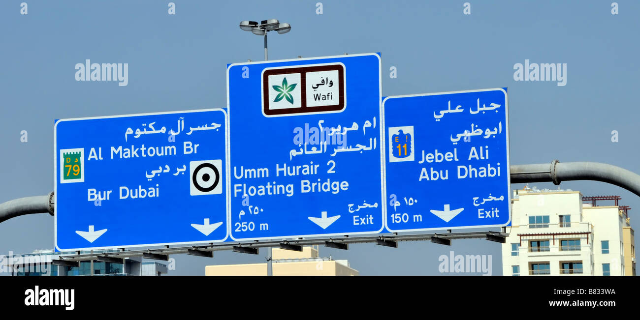 Dubai Blue bilingue autoroute SLIP sortie destination route panneau Portique au-dessus de la circulation paysage urbain ensoleillé Émirats arabes Unis eau Moyen-Orient Banque D'Images