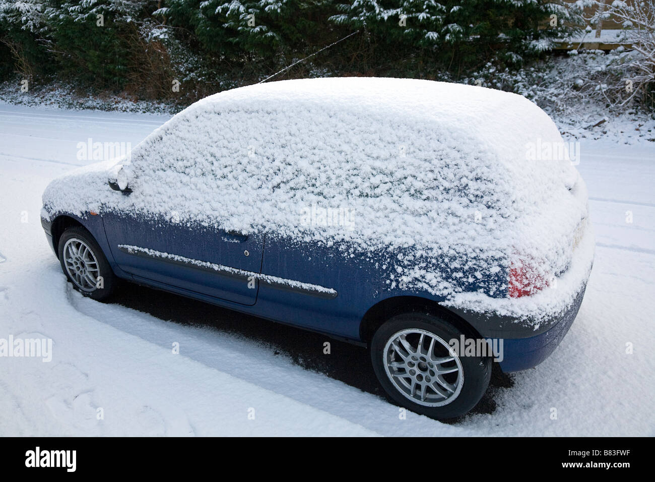 La neige a couvert garé la voiture à hayon Banque D'Images