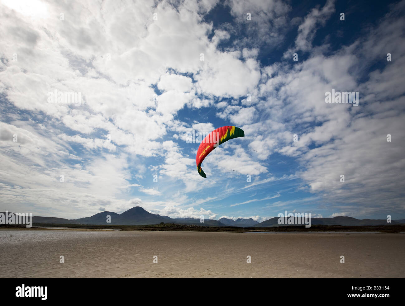 Cerf-volant de couleur/profil aérodynamique sur sandy beach écossais avec des montagnes en arrière-plan Banque D'Images