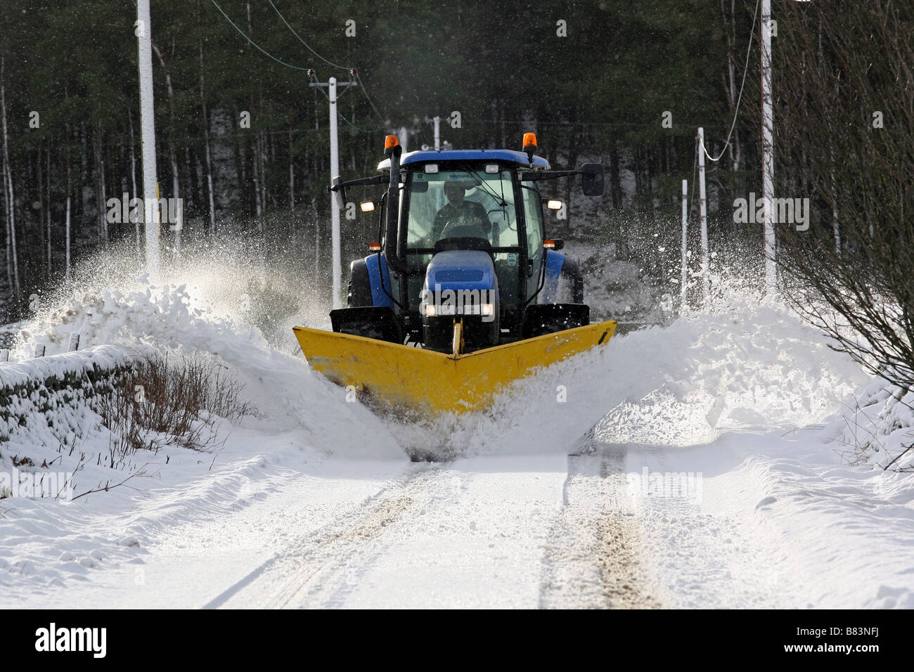 Un tracteur agricole avec charrue attaché clearing routes rurales dans l'Aberdeenshire, Scotland, UK, de la neige en hiver Banque D'Images