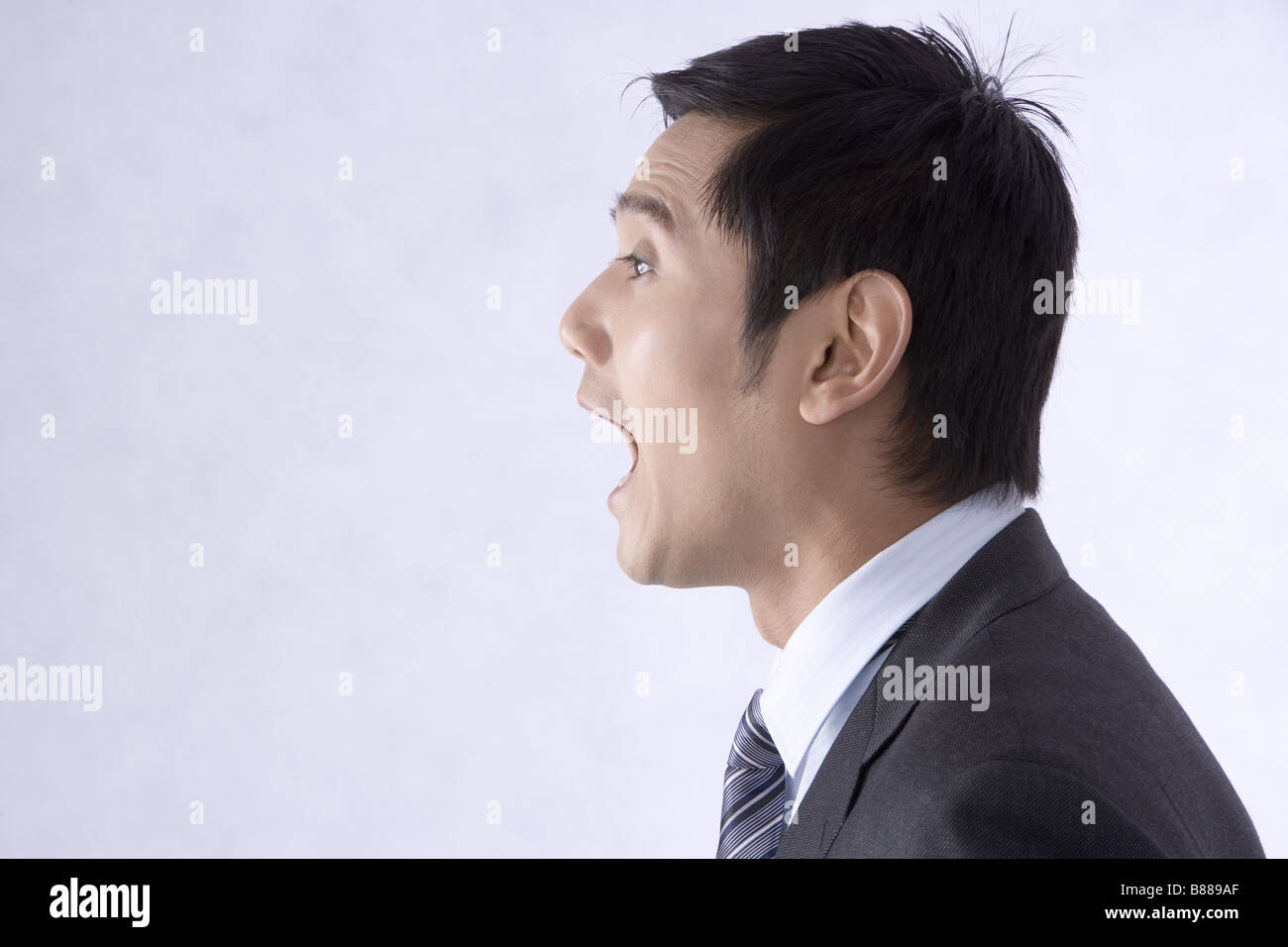 Young businessman shouting avec large bouche ouverte, portrait de profil Banque D'Images