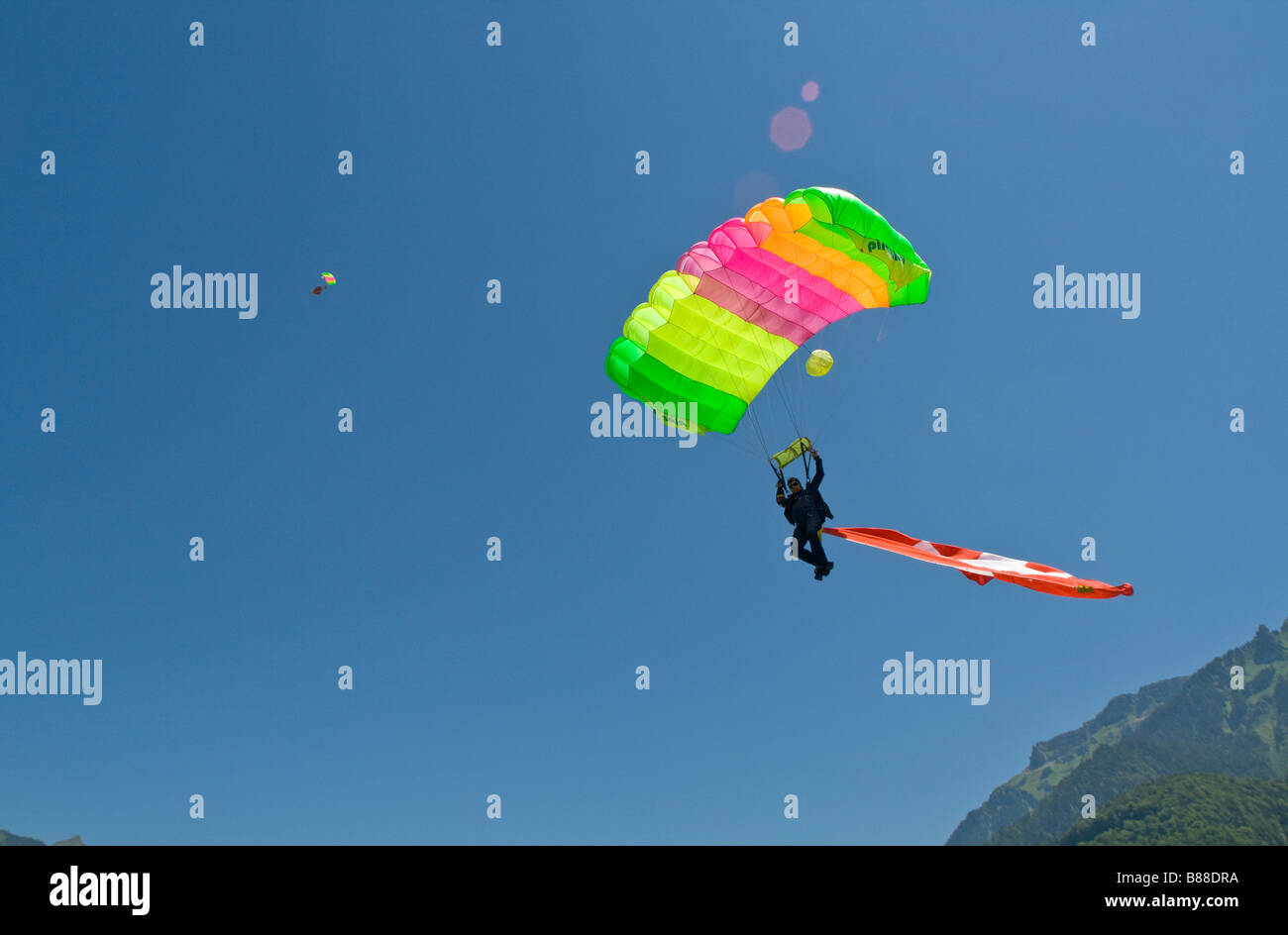 Parachutiste sous voilure va atterrir avec un grand drapeau suisse derrière lui.Avec cette démo jump le plongeur est représente le sport. Banque D'Images