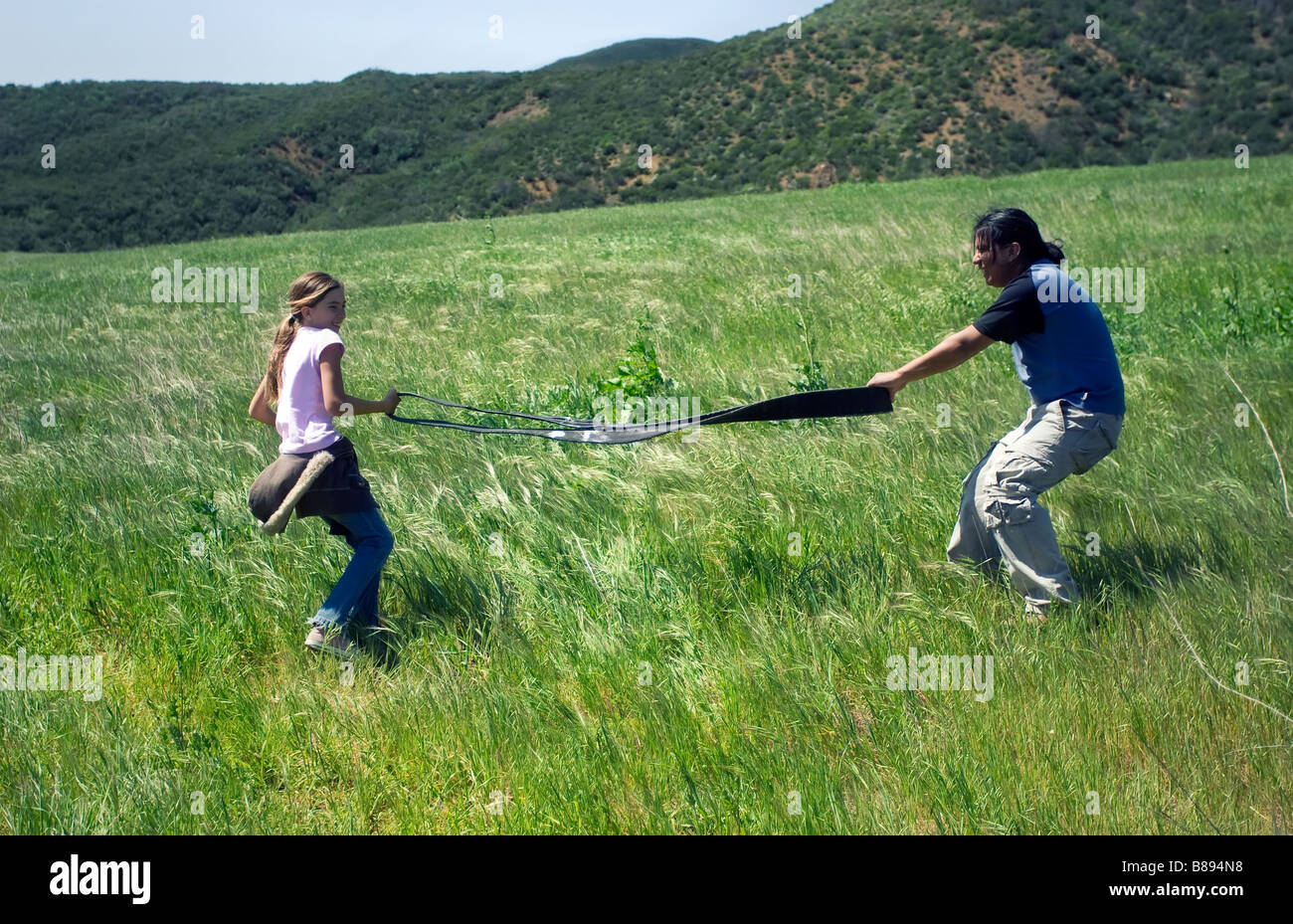 Un garçon et une jeune fille jouer un jeu de tir à la corde dans un champ vert Banque D'Images