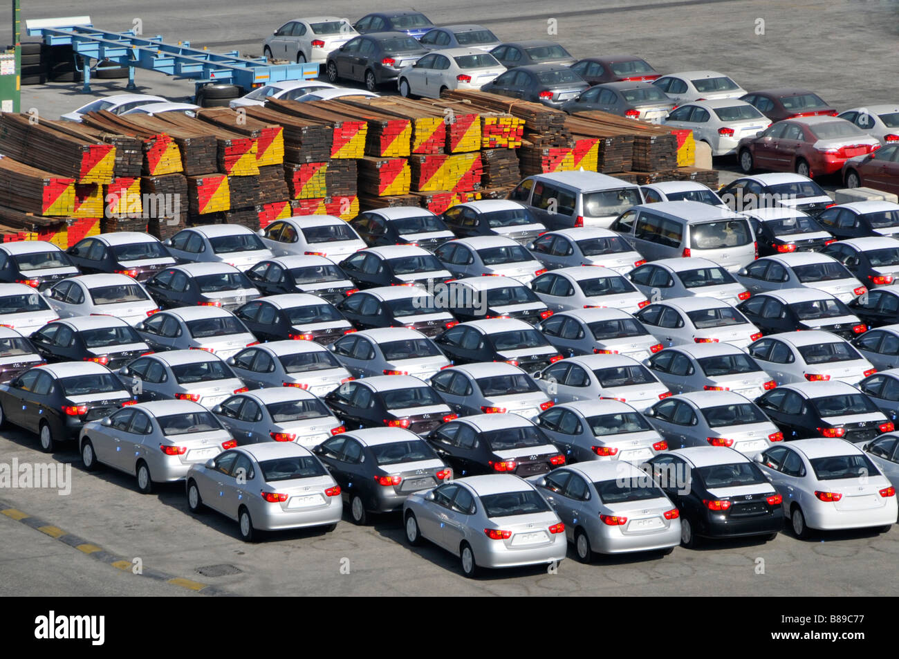 Vue aérienne de Bahreïn regardant vers le bas et de près sur les activités de stockage à quai pour les voitures neuves importées et les gros tas de bois en attente de distribution Banque D'Images