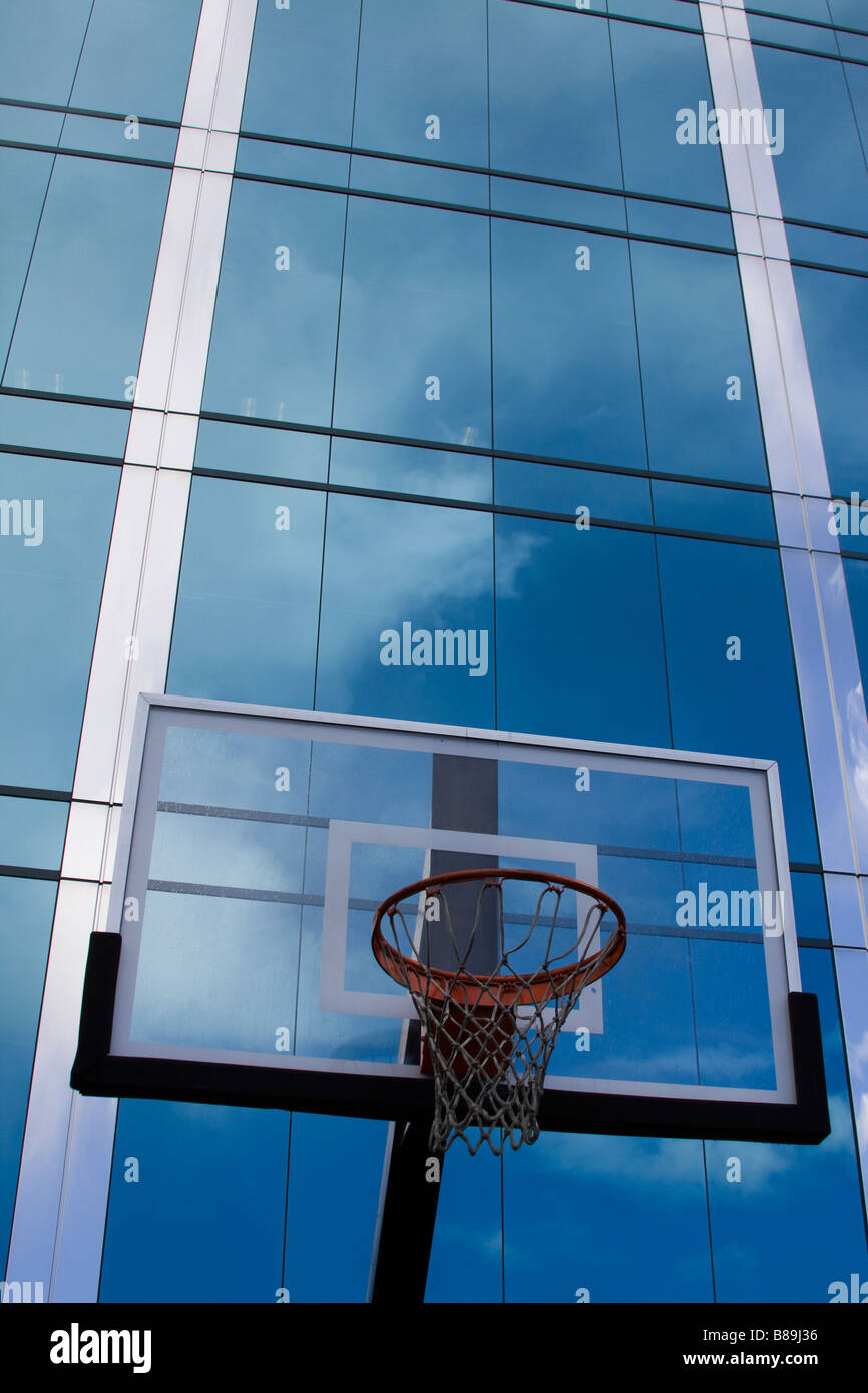 Panier de basket-ball avec panneau en verre en face de verre élégant immeuble de bureaux modernes en raison de nuages dans la surface Banque D'Images