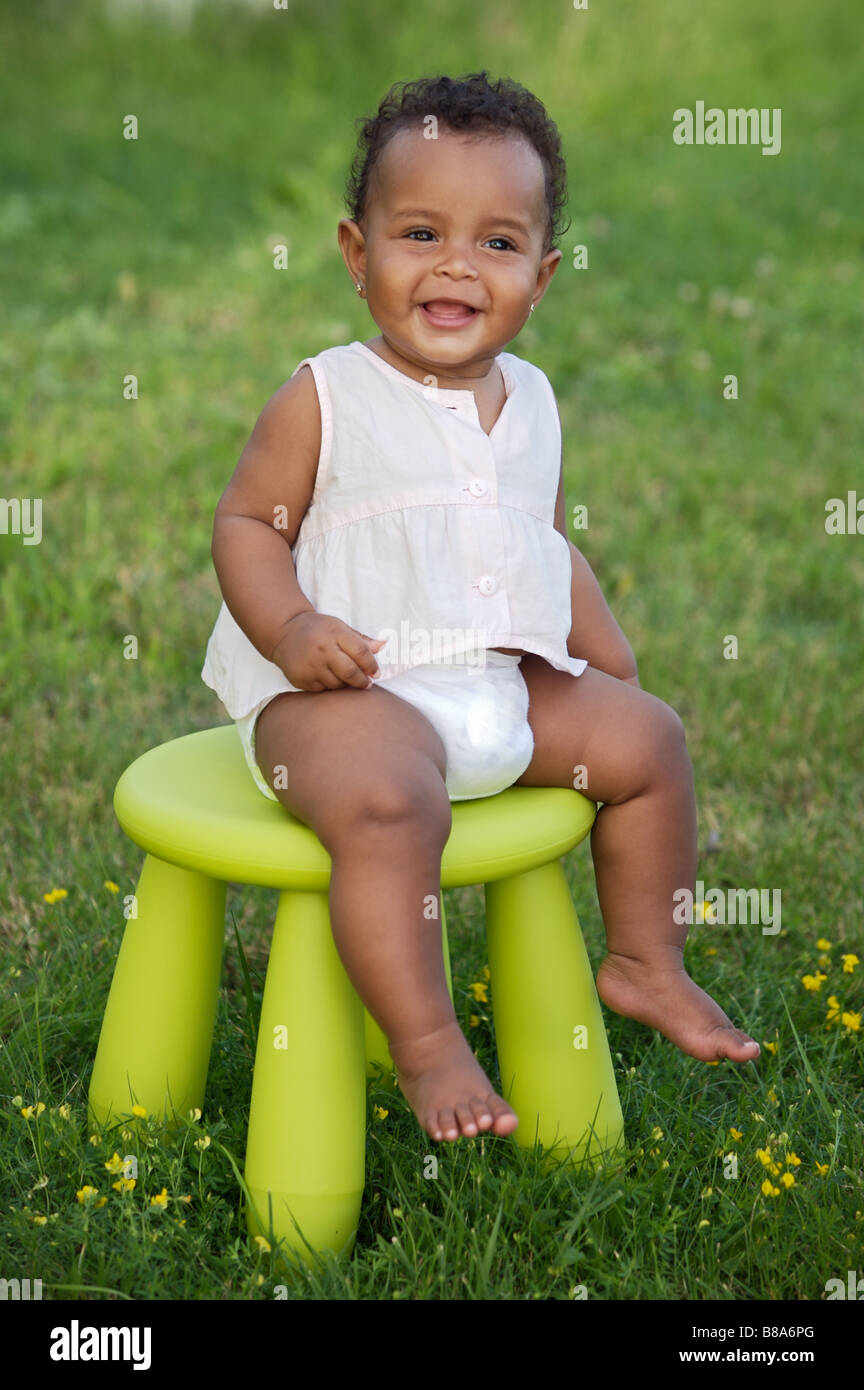 Adorable enfant jouant avec une chaise dans le jardin Banque D'Images