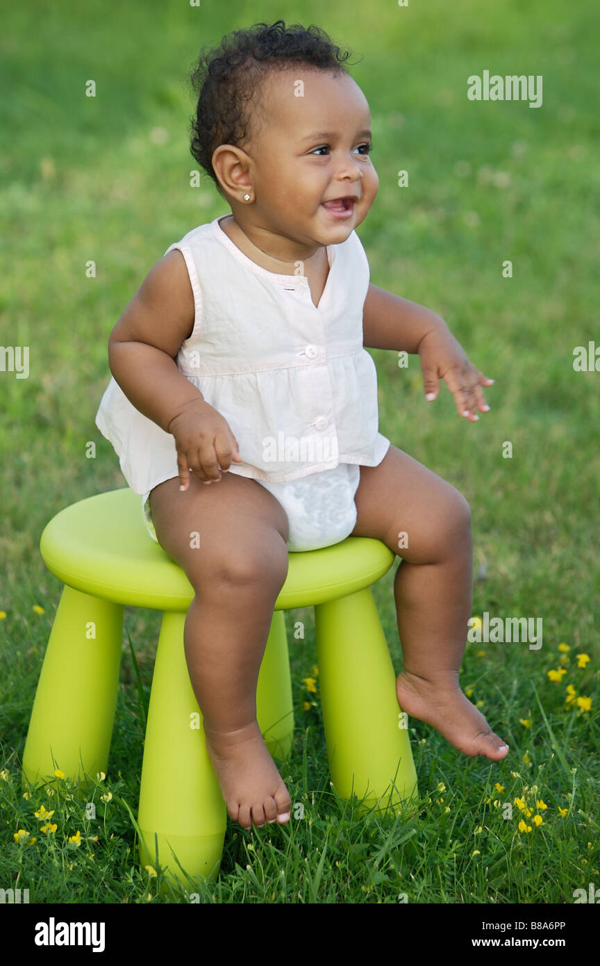 Adorable enfant jouant avec une chaise dans le jardin Banque D'Images