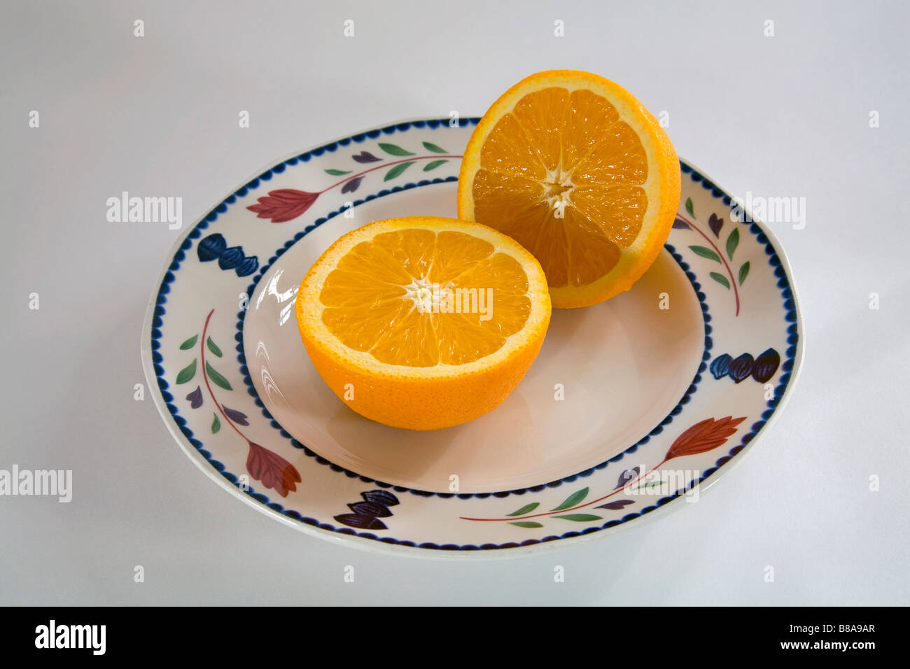 Nature morte de légumes fruits deux moitiés d'une orange Navel uniformément en tranches sur une assiette Banque D'Images