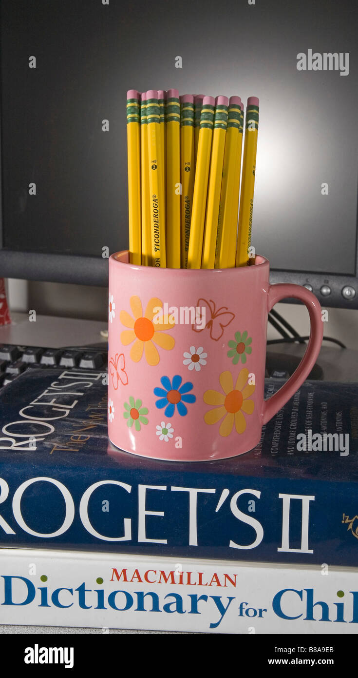 Une tasse de Ticonderoga numéro deux ou plomb mine graphite sur un dictionnaire et une thesarasus devant un ordinateur Banque D'Images