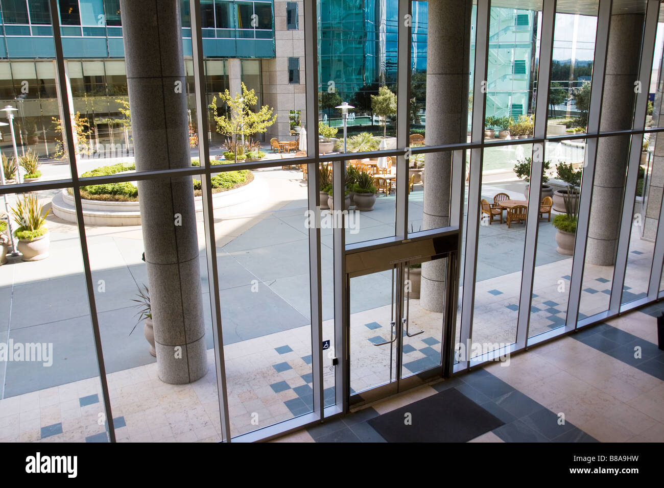 Agréable cour patio salon vu à travers la vitre d'entrée d'un immeuble de bureaux moderne complexe Banque D'Images