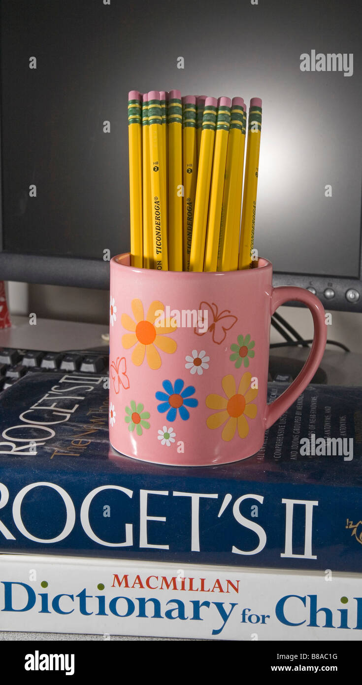 Une tasse de Ticonderoga numéro deux ou plomb mine graphite sur un dictionnaire et une thesarasus devant un ordinateur Banque D'Images