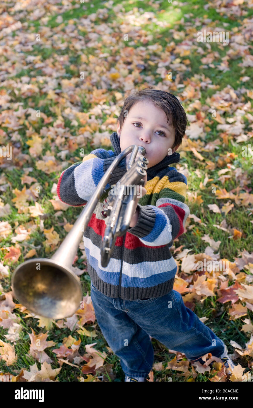 Trois ans joue avec sa trompette à l'extérieur sur un jour d'automne Banque D'Images