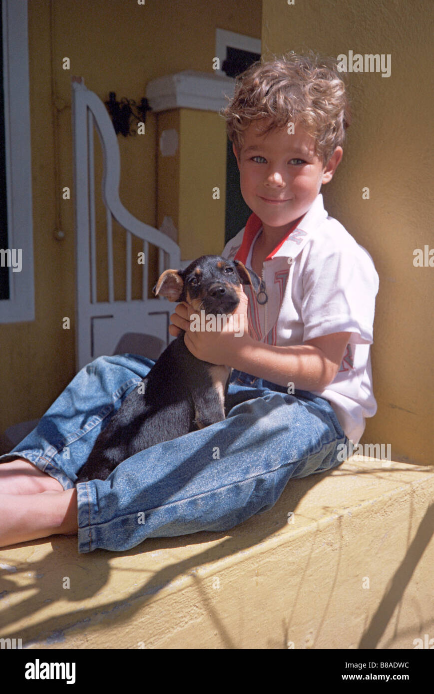 Un jeune garçon de la région montre fièrement son nouveau chien chez lui à Willemstad, sur l'île de Curaçao aux Antilles néerlandaises Banque D'Images