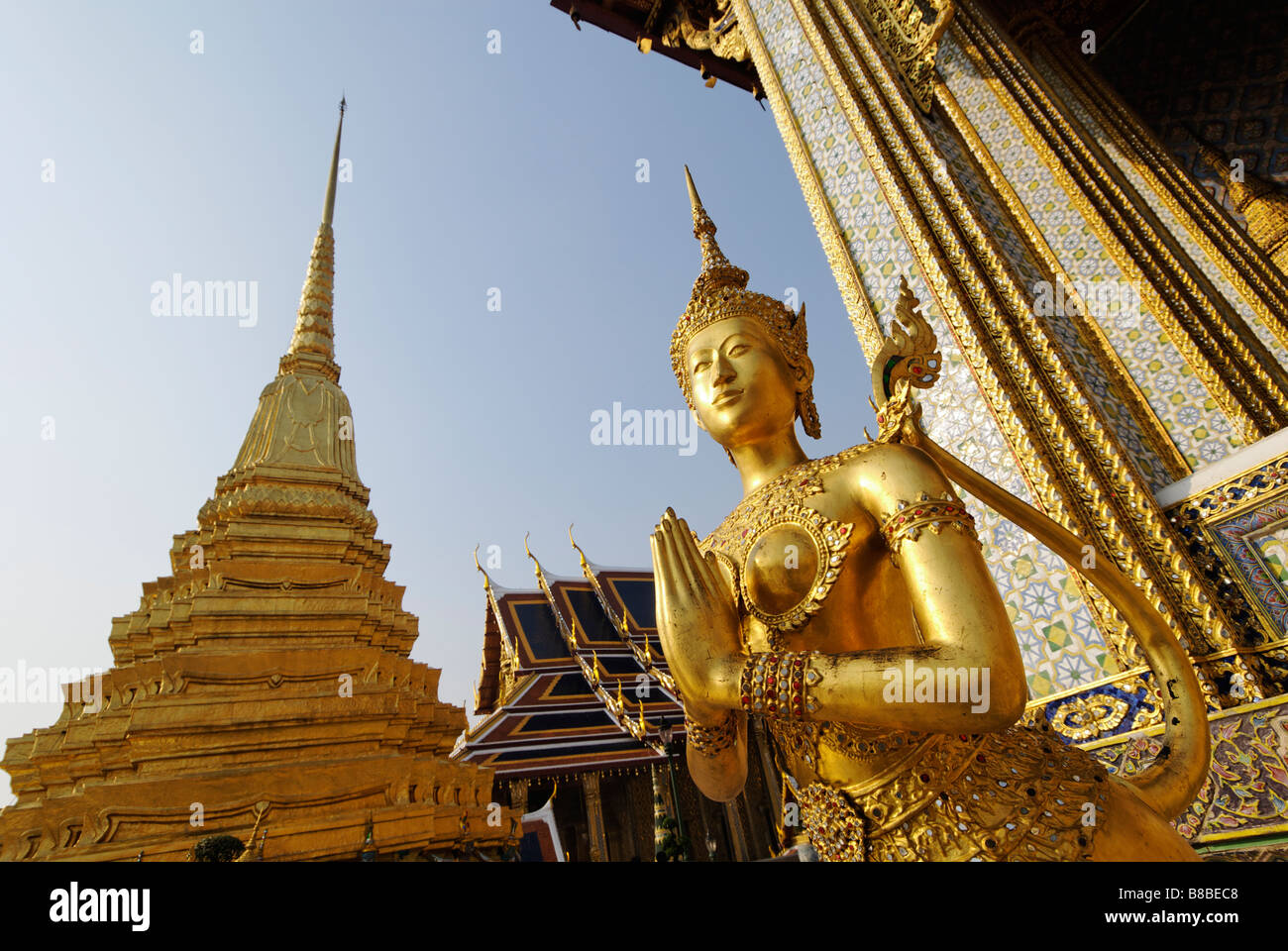 Kinnara formant une statue d'or Wai hand gesture - Wat Phra Kaew et le Grand Palais dans le centre de Bangkok en Thaïlande Banque D'Images