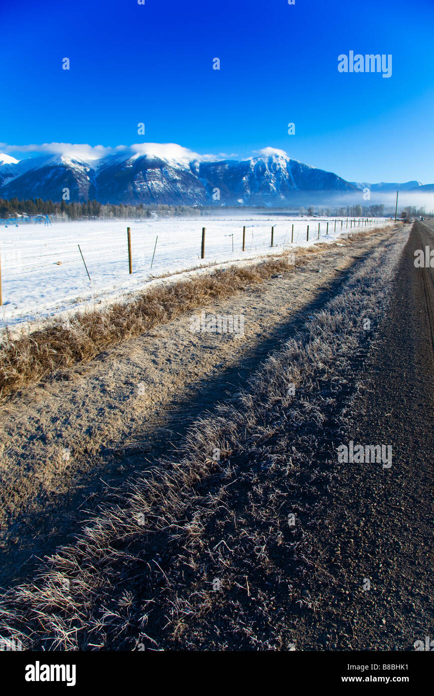 Fossé de drainage le long de la Route 93 East Kootenay BC Canada avec ses montagnes couvertes de neige dans la distance et ciel bleu clair, Canada Banque D'Images
