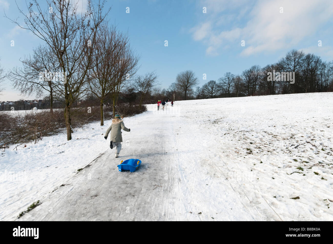 Enfant tirant un traîneau en montée sur Hampstead Heath couvert de neige, Londres, Angleterre, Royaume-Uni Banque D'Images