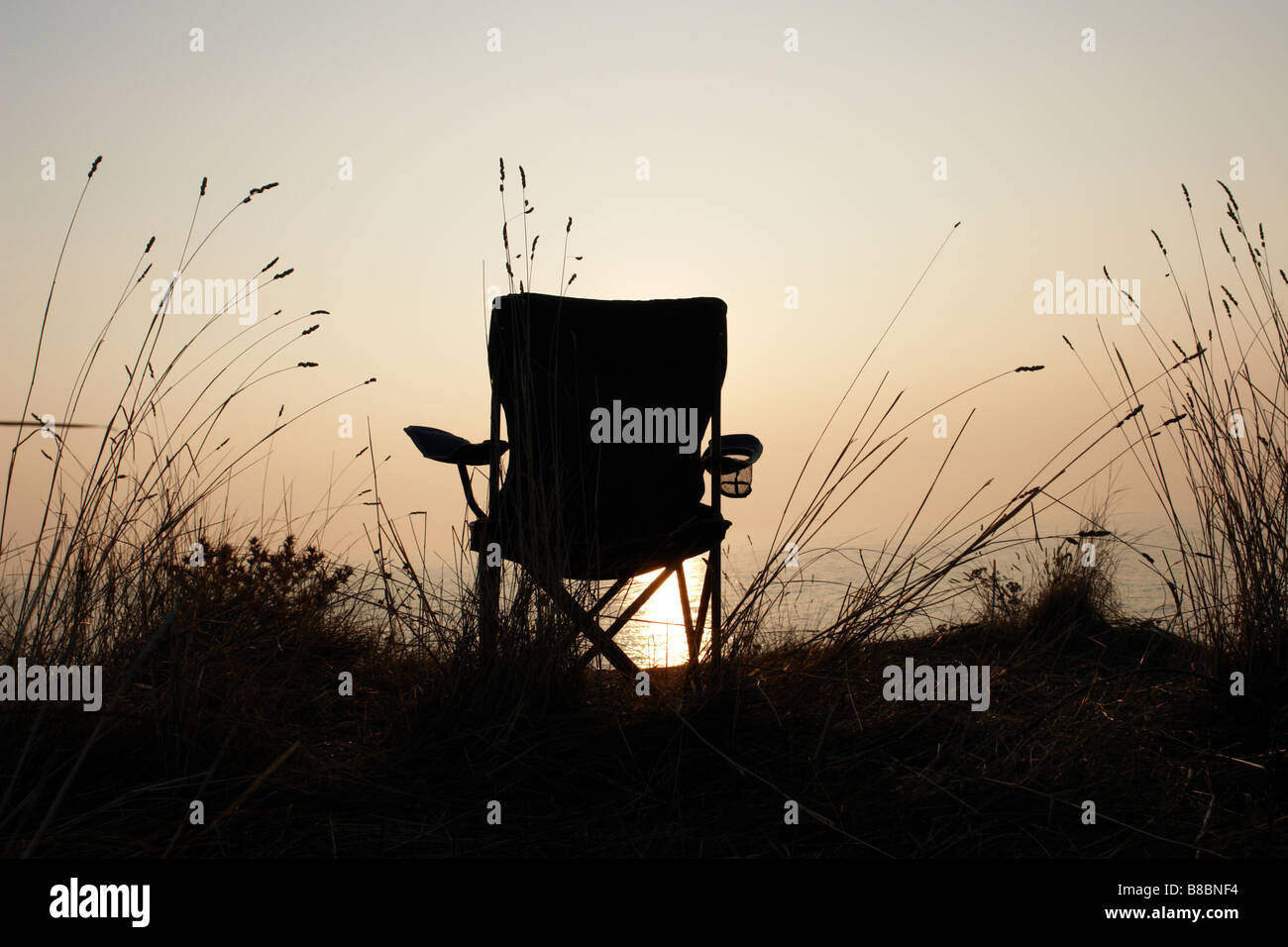 Un fauteuil à la mer au coucher du soleil Banque D'Images