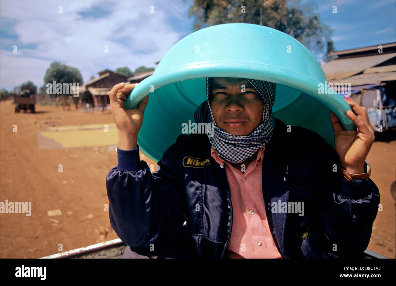 L'homme se sert de lavage plastique seau comme parapluie, Banlung, la province de Ratanakiri, au Cambodge Banque D'Images