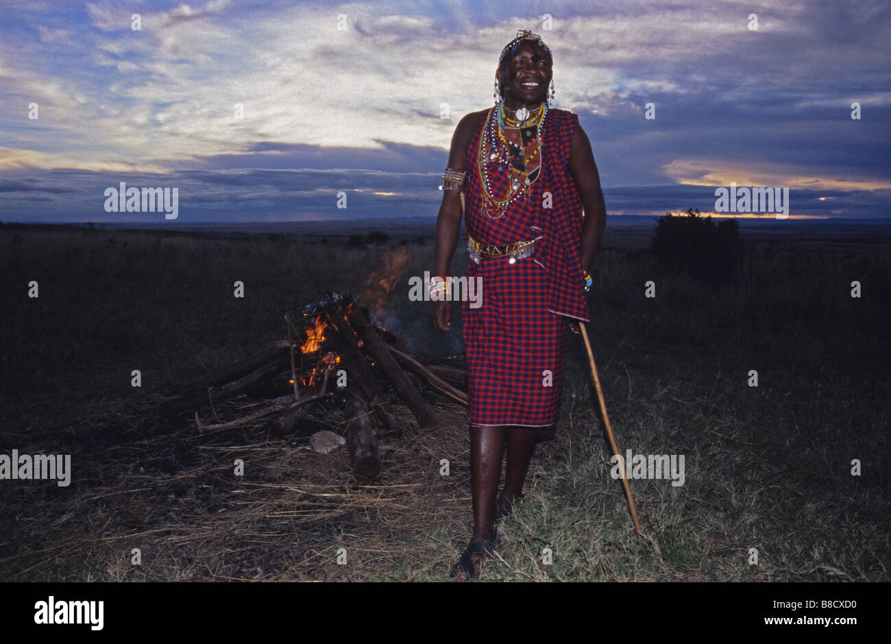 Un guerrier Masai se distingue par son feu au coucher du soleil sur le Masai Mara, Kenya. Banque D'Images