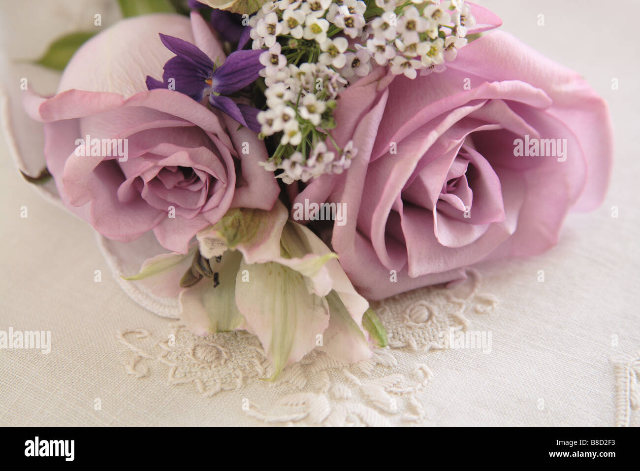 De couleur lavande avec des roses violettes, l'alstroemeria et alyssum sur fleurs brodées Banque D'Images