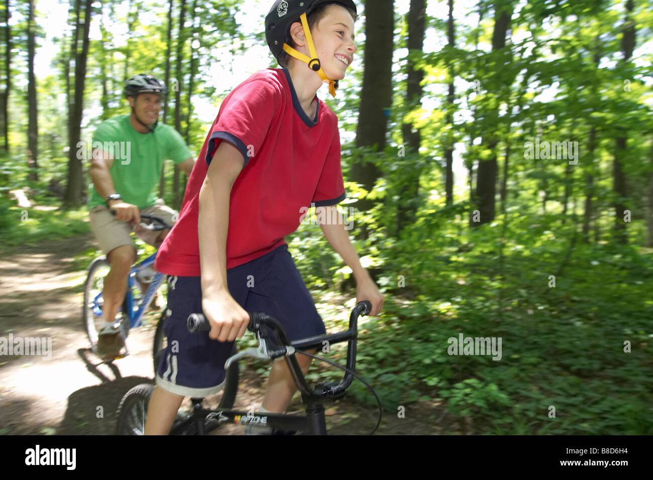 Père Son Riding Bikes Trail à travers bois Banque D'Images