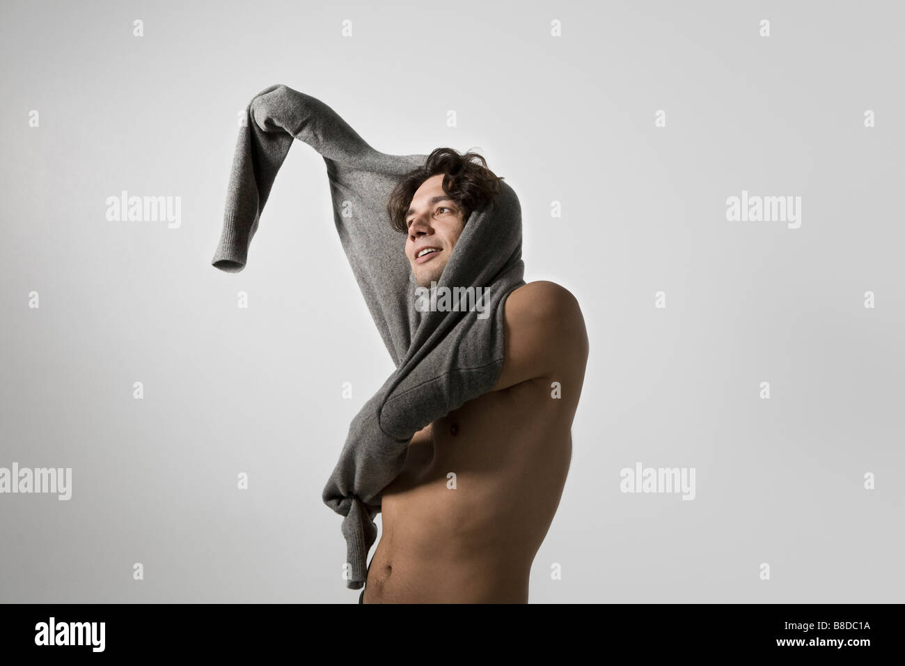 Mid-adult man putting on sweater Banque D'Images
