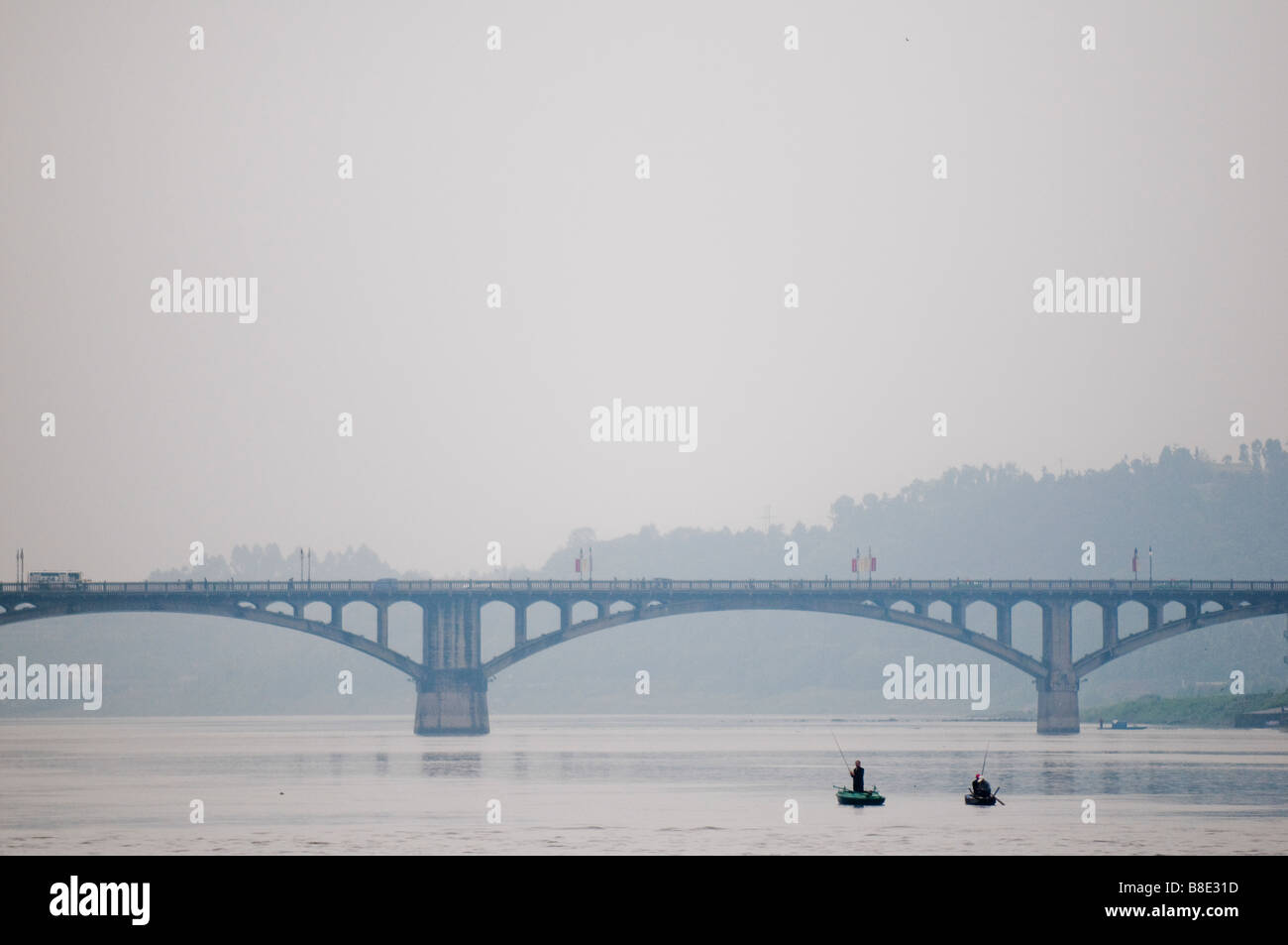 Dans de petits bateaux de pêcheurs qui se profile au cours de la journée par un pont sur une rivière dans la province du Sichuan, Chine Banque D'Images