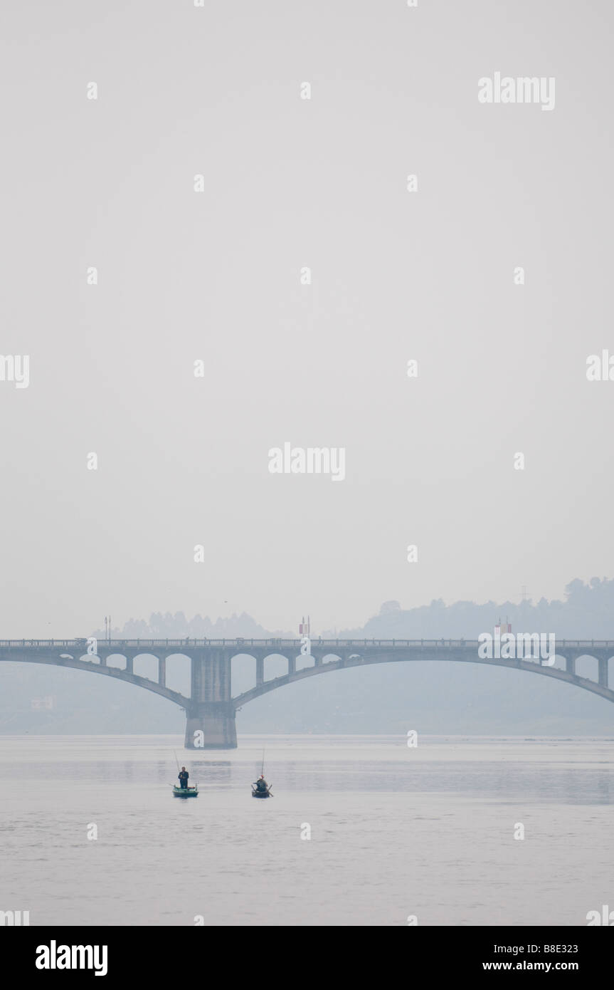 Dans de petits bateaux de pêcheurs qui se profile au cours de la journée par un pont sur une rivière dans la province du Sichuan, Chine Banque D'Images