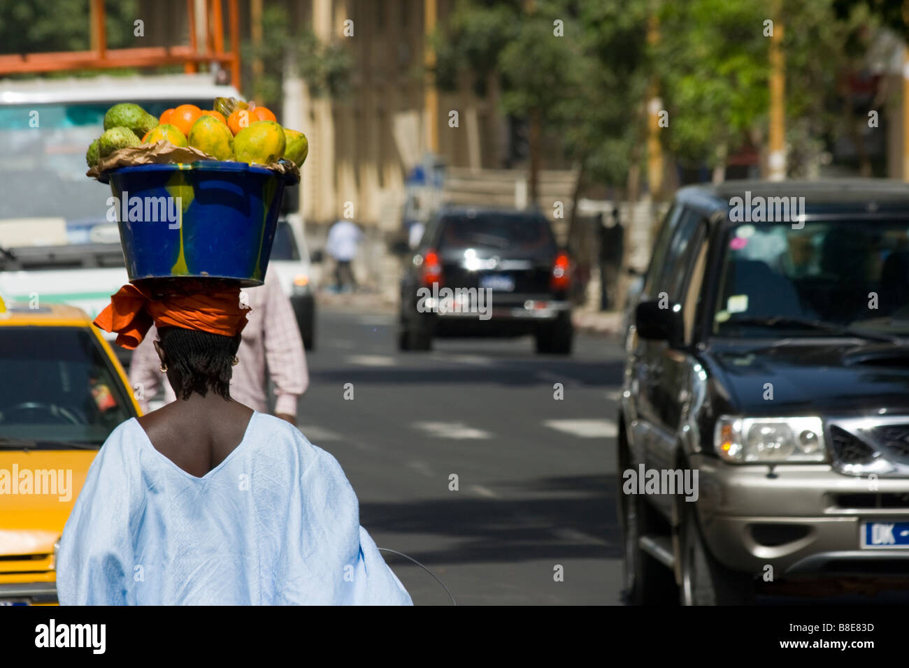 Femme transportant les papayes sur sa tête dans les rues de Dakar Sénégal Banque D'Images