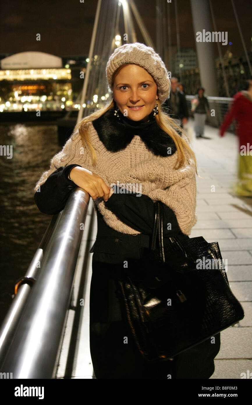 Blonde Jeune Fille ukrainienne portant des vêtements d'hiver se tenant debout sur la passerelle du millénaire dans la nuit Banque D'Images