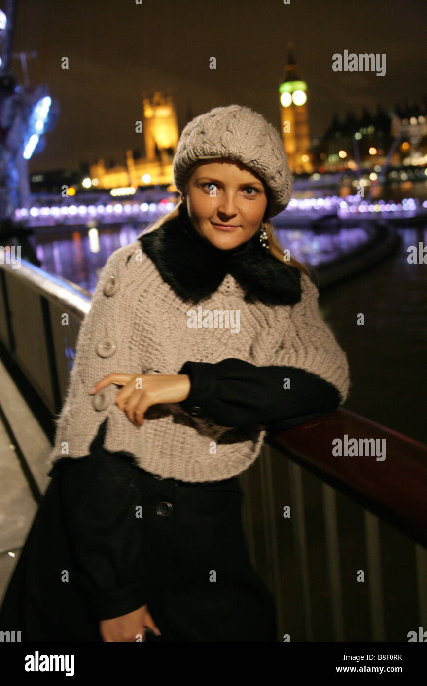 Blonde Jeune Fille ukrainienne portant des vêtements d'hiver se tenant sur la rive sud en face du Palais de Westminster de nuit Banque D'Images