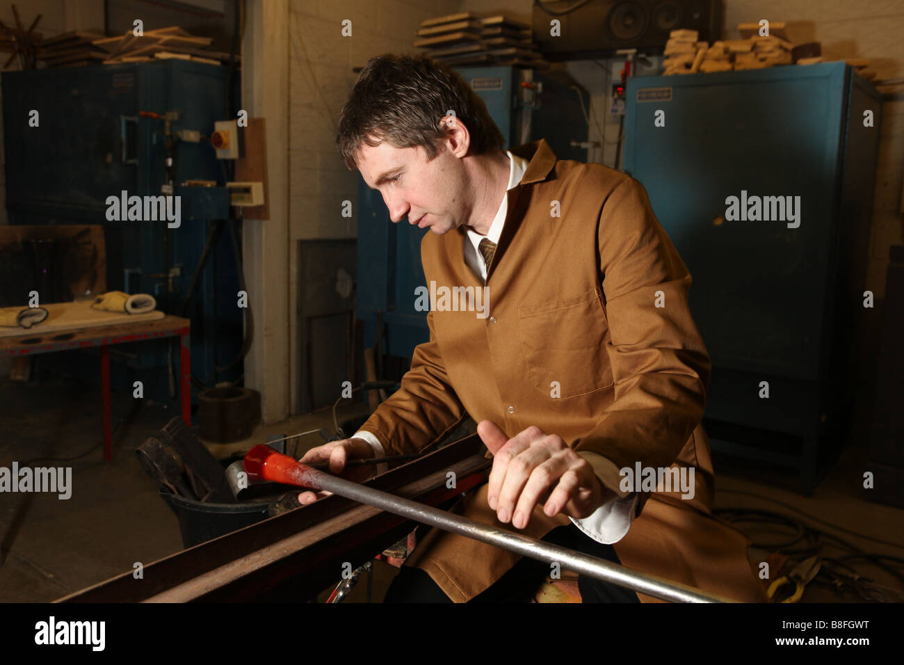 Un souffleur de verre professionnel prend du verre en fusion sur une chaudière prête à exploser et la forme dans un vase ou verre ornement Banque D'Images