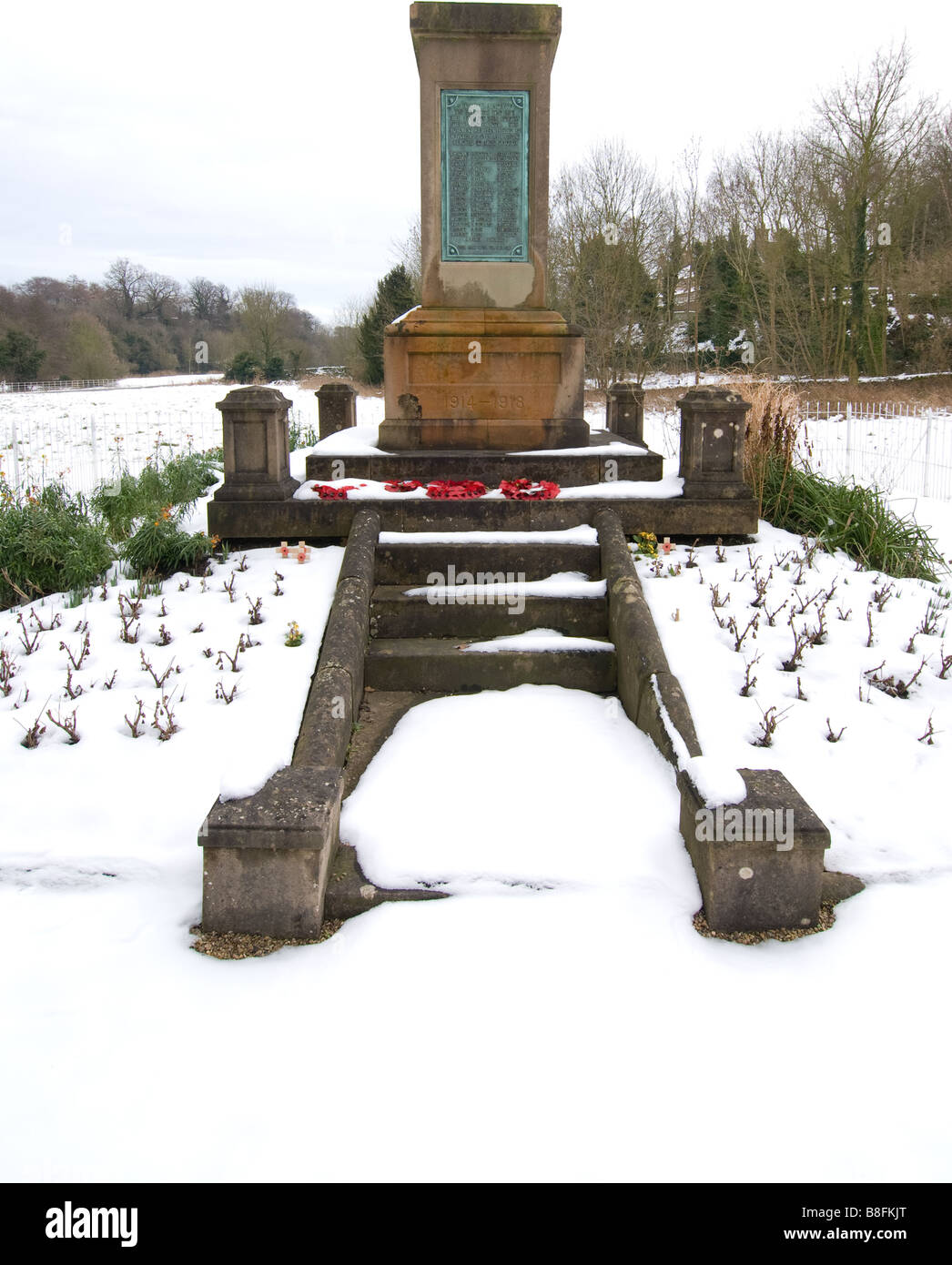 Des couronnes de pavot fixées à un mémorial de guerre avec un n'aime pas la neige de l'automne. Banque D'Images