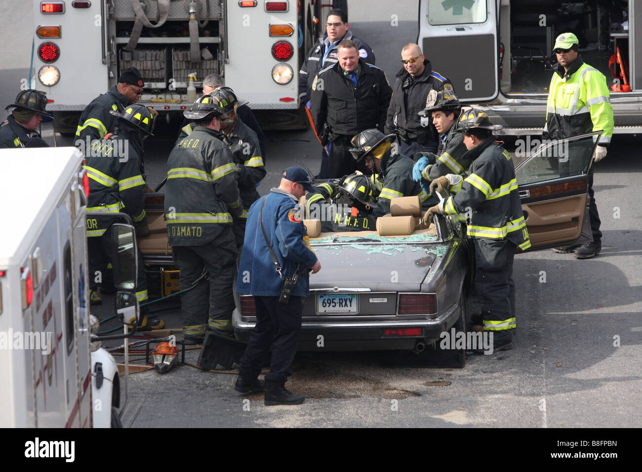 Les pompiers se tirer une femme d'une auto Jaguar après la découpe du toit à la suite d'un accident avec un tracteur semi-remorque. Banque D'Images