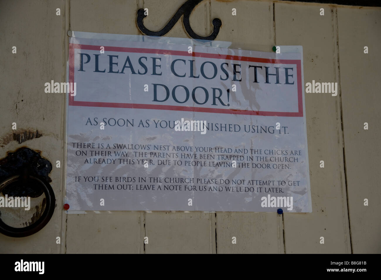 Veuillez fermer la porte signe sur une porte de l'église d'arrêter de faire l'intérieur à traped hirondelles Penmon Église, Anglesey, au nord du Pays de Galles Banque D'Images