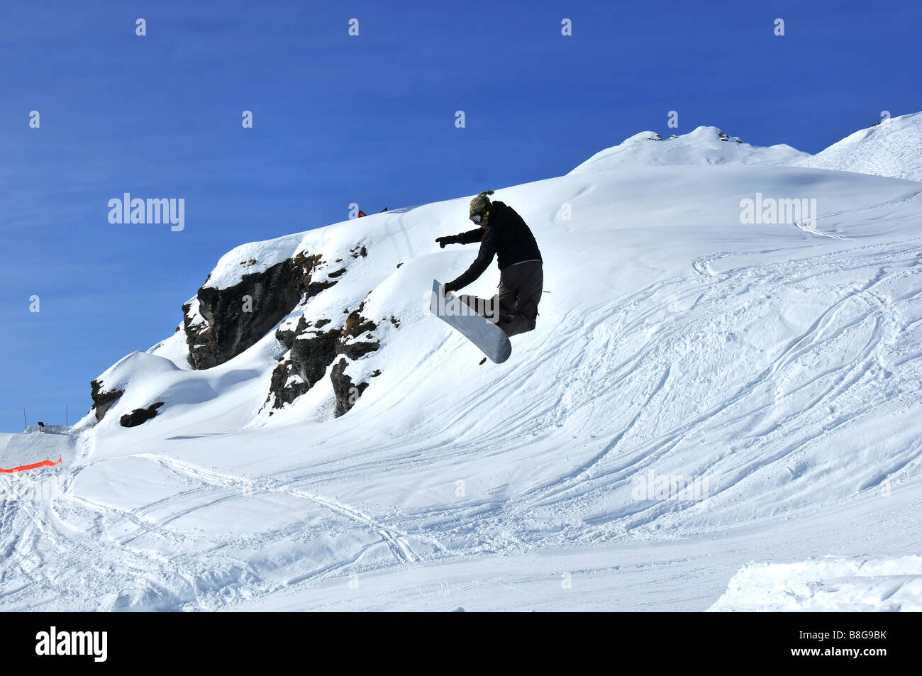 Snowboarder effectuant un saut et poser Banque D'Images