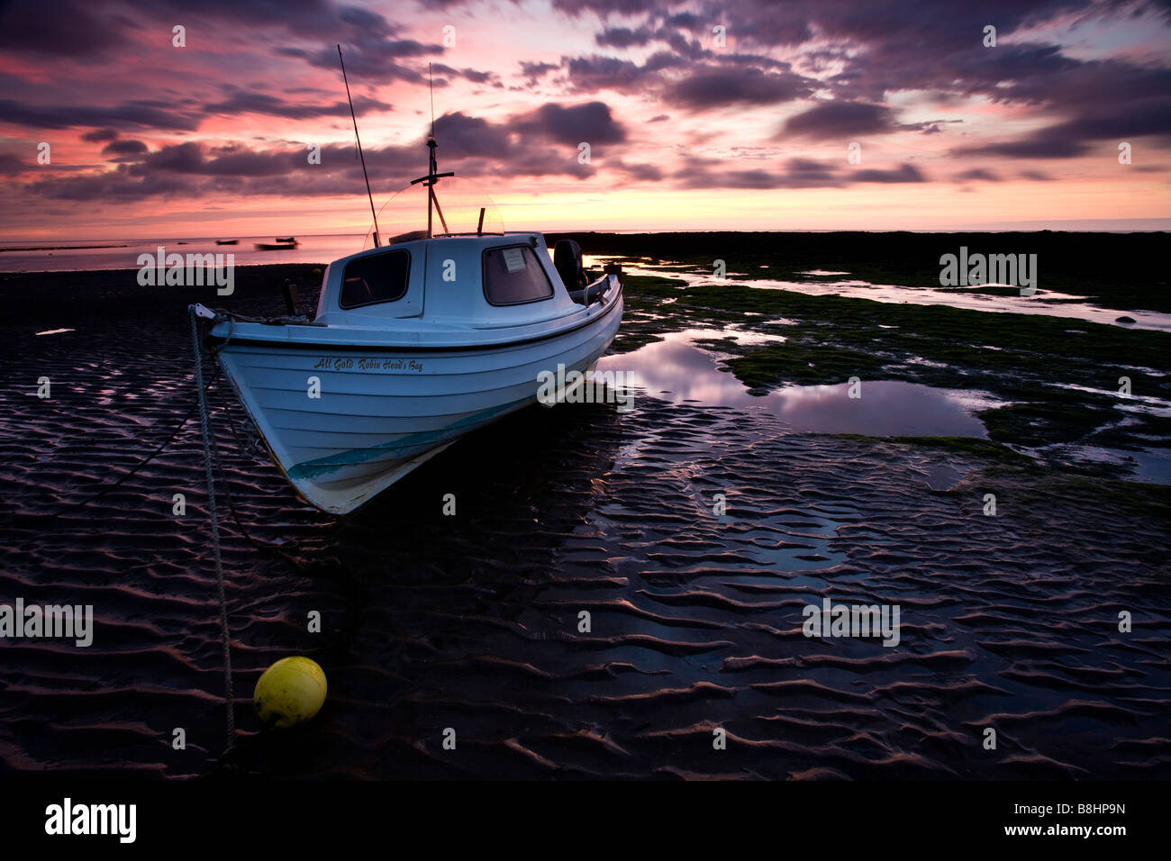 Un petit bateau échoué à marée basse à l'aube dans la région de Scarborough, Yorkshire du Nord Banque D'Images