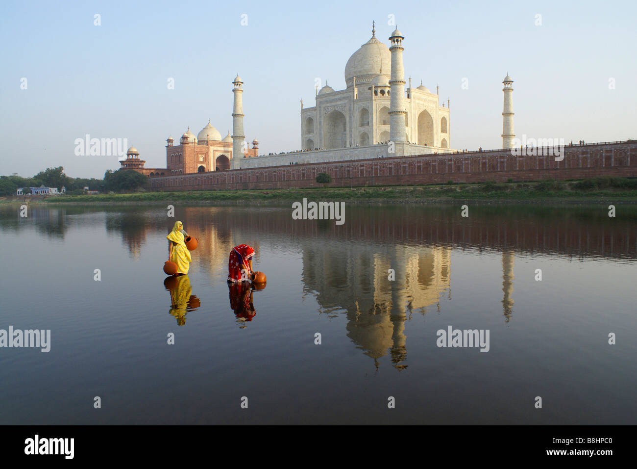 Les femmes obtenir de l'eau à partir de la rivière Yamuna avec Taj Mahal en arrière-plan, Agra, Inde Banque D'Images